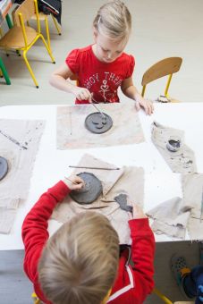 Dzieci modelują różne postaci na swoich płaskorzeźbach.