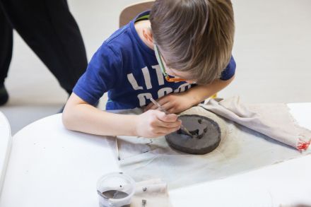 Chłopiec pracuje nad swoją płaskorzeźbą - rybą.