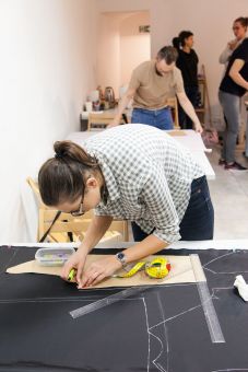 Kobieta wycina kawałek materiału nożykiem tapicerskim.