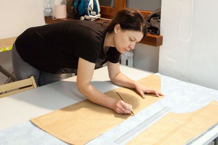 Kobieta odrysowuje ołówkiem wzór na materiale.