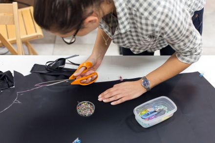 Kobieta wycina nożyczkami krój na kurtkę przeciwdeszczową.