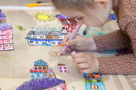 Dziewczynka rysuje następne elementy do plakatu.