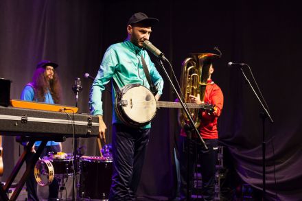 Zbliżenie na wokalistę. W tle dwaj pozostali muzycy.