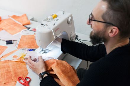 Zbliżenie na dłonie mężczyzny, który szyje na maszynie.