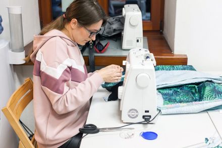 Dziewczyna przygotowuje materiał do zszycia go na maszynie.