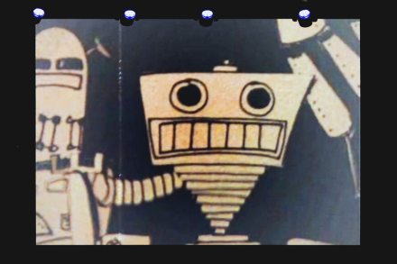 Na ścianie wyświetlany jest czarno-biały film o robotach.  Na zdjęciu przedstawione są dwa roboty - większy i mniejszy.