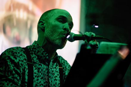 Wokalista trzyma w ręce statyw od mikrofonu.