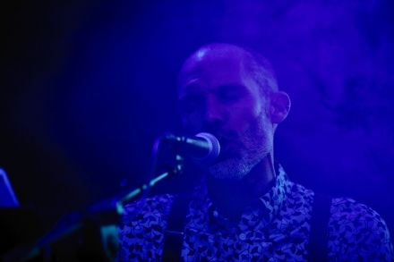 Wokalista przed mikrofonem. Śpiewa z zamkniętymi oczami.