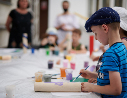 Chłopiec zaczyna malować ceramiczny walec.