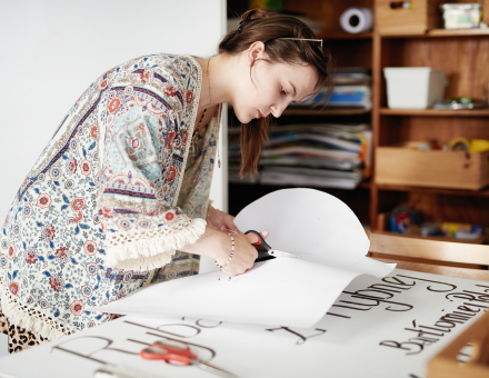 Kobieta wycina koło z kartonu, które będzie podstawą do stworzenia znaku drogowego.