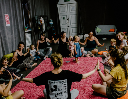 Uczestnicy warsztatów siedzą w kole i trzymają się za ręce.