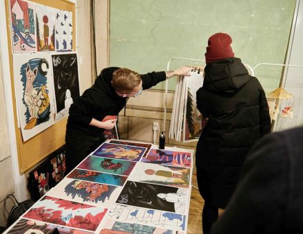 Stoisko z plakatami i grafikami. Ogląda je kobieta.