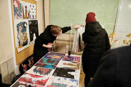 Stoisko z plakatami i grafikami. Ogląda je kobieta.