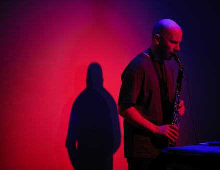 Wacław Zimpel gra na saksofonie. Scena podświetlona na czerwono i niebiesko.