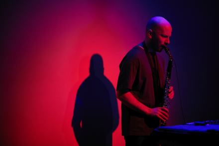 Wacław Zimpel gra na saksofonie. Scena podświetlona na czerwono i niebiesko.