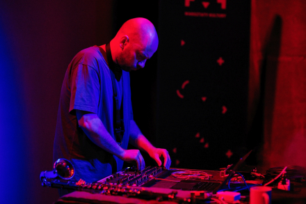 Mężczyzna obsługuje konsolę. Scena podświetlona jest czerwonym światłem.