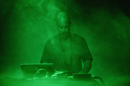 Scena podświetlona na zielono. Zbliżenie na twarz muzyka.