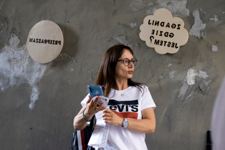 Kobieta robi selfie z tabliczką z napisem "zgadnij gdzie jestem?".