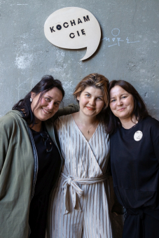 Trzy kobiety pod tabliczką z napisem "kocham Cię".