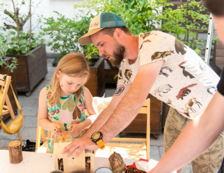 Mężczyzna pomaga dziewczynce w budowie domku dla pszczół.