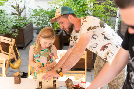 Mężczyzna pomaga dziewczynce w budowie domku dla pszczół.