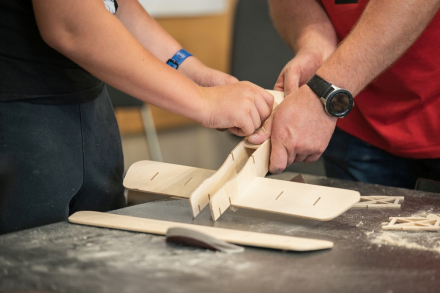 Zbliżenie na stół, na którym animator z chłopcem budują samolot.