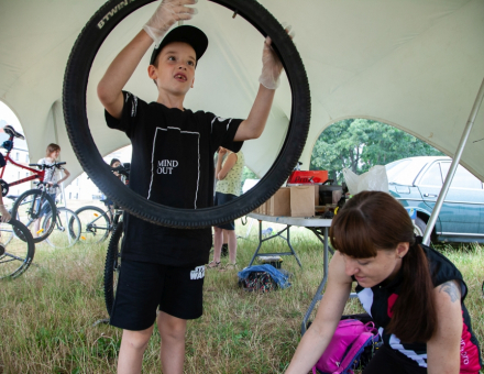 Chłopiec podnosi do góry oponę od roweru.