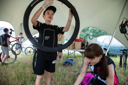 Chłopiec podnosi do góry oponę od roweru.