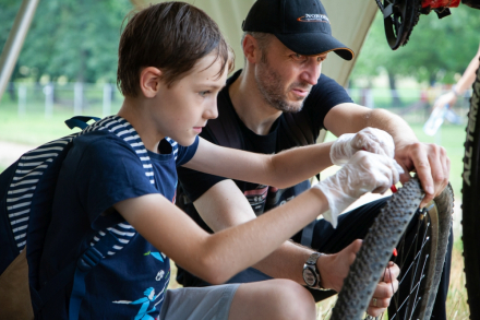 Mężczyzna trzyma oponę. Chłopiec sprawdza, czy jest napompowana.