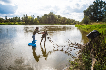 Mężczyzna stoi w wodzie. Zbiera materiał do plecenia.