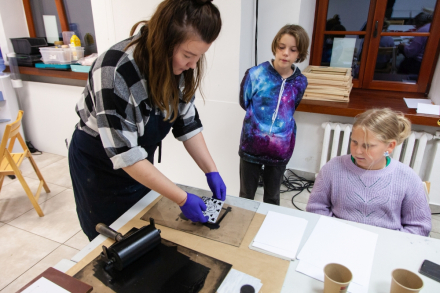 Prowadząca pomaga dzieciom w zrobieniu linorytu.