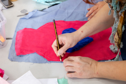 Dłoń kobiety, która rysuje na materiale kształt termoforu, odrysowując go od gotowej już przytulanki.