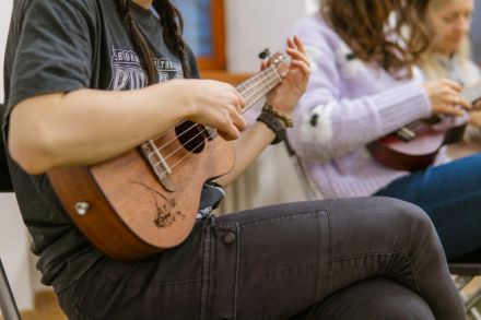 Kolana kobiety, na których opiera ukulele i gra.