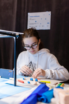 Dziewczynka przesuwa klocek lego po stole.