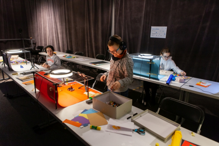 Zdjęcie z oddali. Warsztatowicze siedzą na swoich stanowiskach pracy i robią stopklatki do swoich filmików.