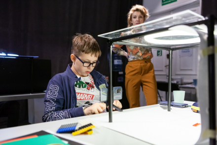 Chłopiec jest skupiony na łączeniu małych elementów.