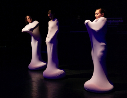 Trzy kobiety w jednakowych kostiumach. Są całe zawinięte materiałem i widać im tylko głowy.