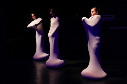 Trzy kobiety w jednakowych kostiumach. Są całe zawinięte materiałem i widać im tylko głowy.