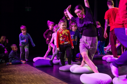 Animatorka pokazuje dzieciom na scenie, jakie kroki mają za nią powtarzać.