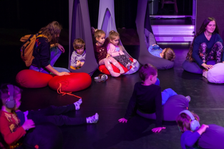 Dzieci siedzą w kokonach na scenie.