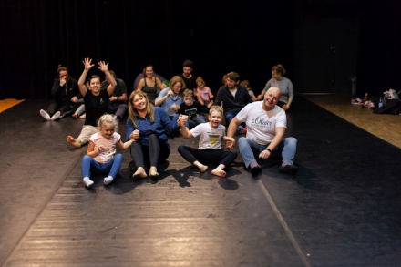 Rodzice z dziećmi siedzą na podłodze i bujają się w prawo i lewo.