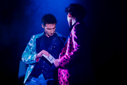 Dwaj mężczyźni stoją koło siebie. Jeden trzyma w ręce kartę.