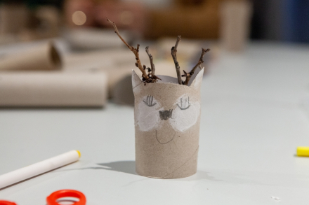 Na stoliku stoi renifer zrobiony z gałązek i papieru toaletowego.