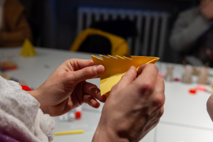 Kobieta robi choinkę z papieru. Ozdoba jest żółta.