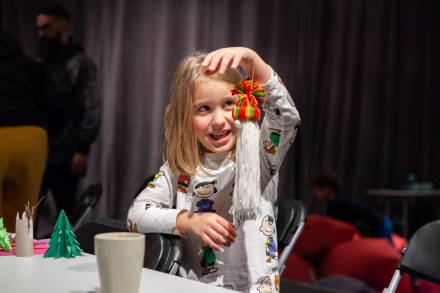 Dziewczynka prezentuje Mikołaja. Ma długą brodę i czerwoną czapkę.