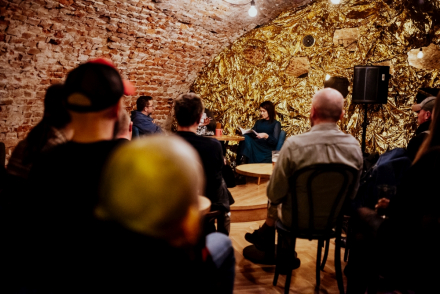 Publiczność siedzi przy stolikach w pubie Bałagan.