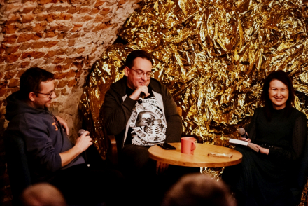 Przy stoliku siedzą Jarek Szubrycht i dwoje prowadzących.