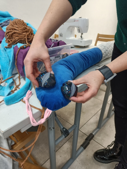 Mężczyzna przymierza guziki, które będą oczami na głowie  węża.