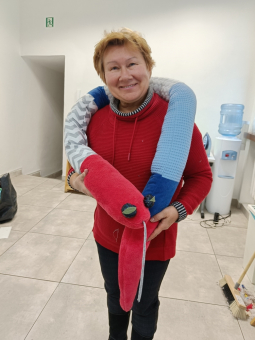 Kobieta w średnim wieku prezentuje swoją pracę - samodzielnie uszytego węża obciążeniowego.