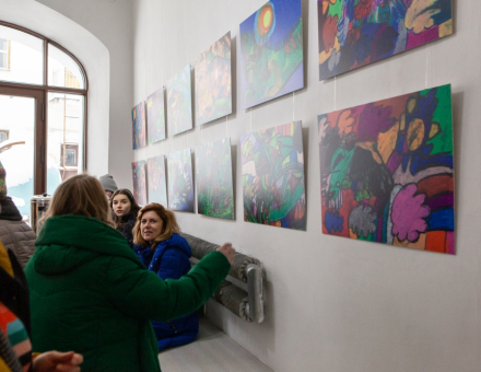 Na ścianie wiszą obrazy namalowane przez Igora Bryzka. Przyglądają się im ludzie.